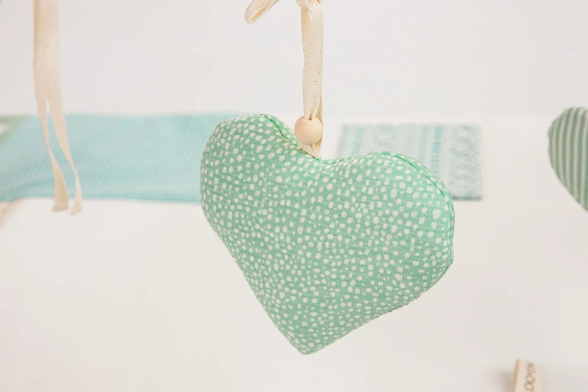 3. Close-up of mint green heart-shaped toy with polka dots on baby activity mat