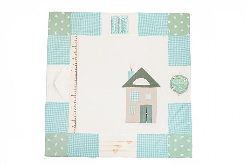 4. Flat lay of mint green baby activity mat with house design and patchwork border