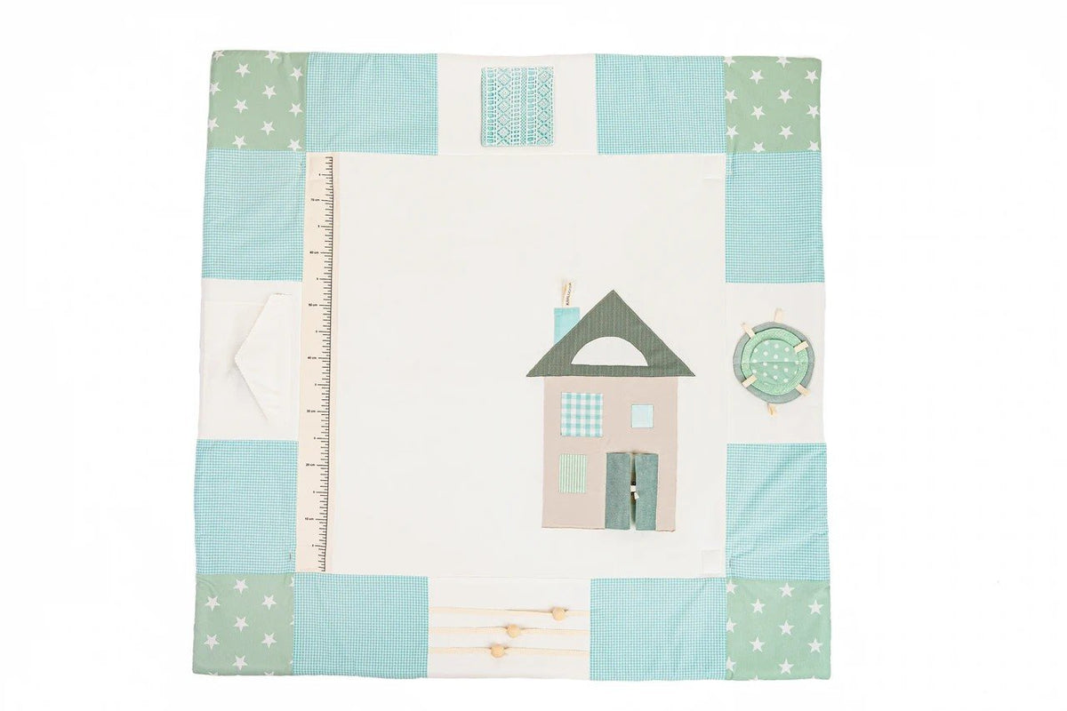 4. Flat lay of mint green baby activity mat with house design and patchwork border