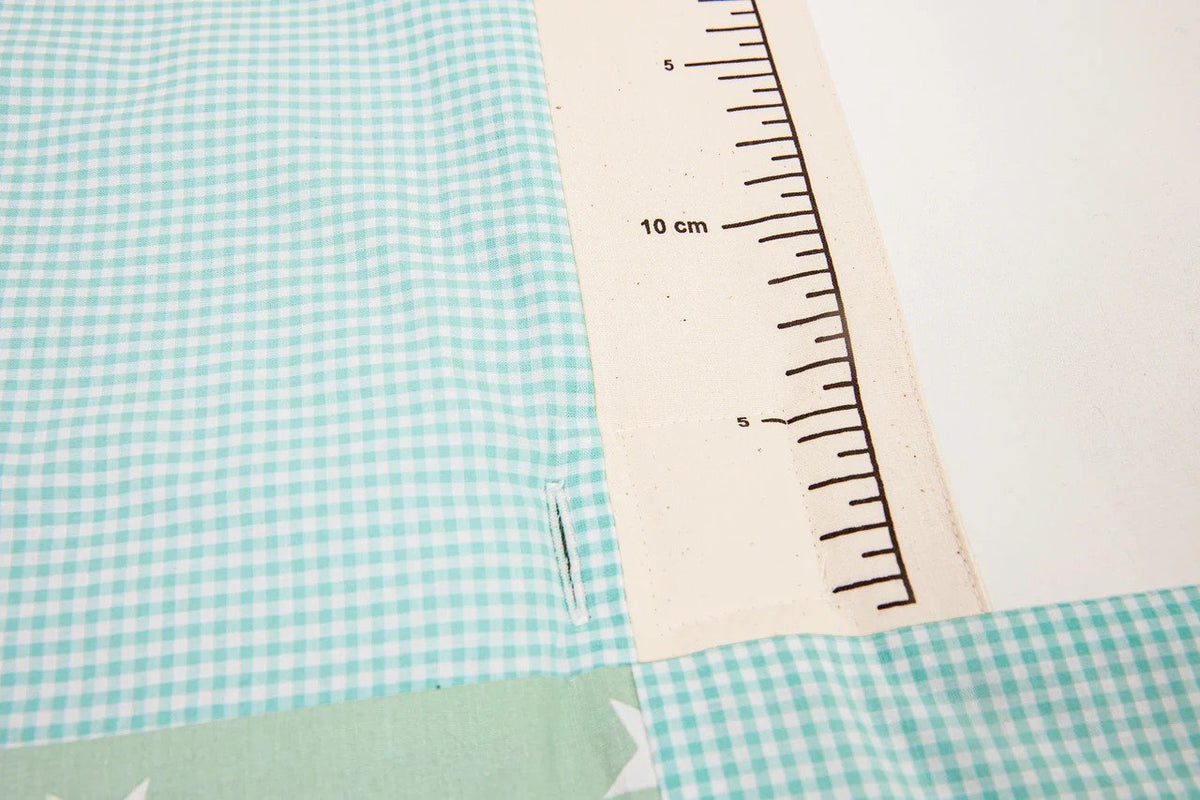 3. Close-up of ruler design on mint green gingham fabric of baby activity mat