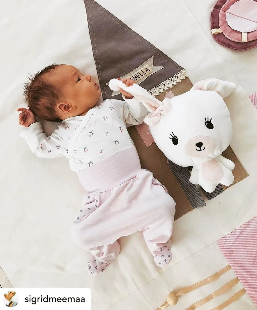 1. Baby lying on pink activity mat with plush toy and decorative house detail