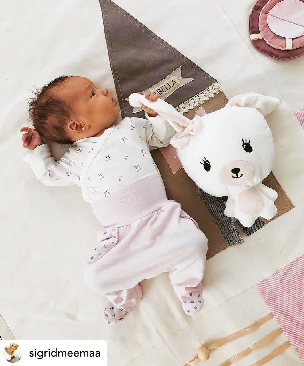 1. Baby lying on pink activity mat with plush toy and decorative house detail