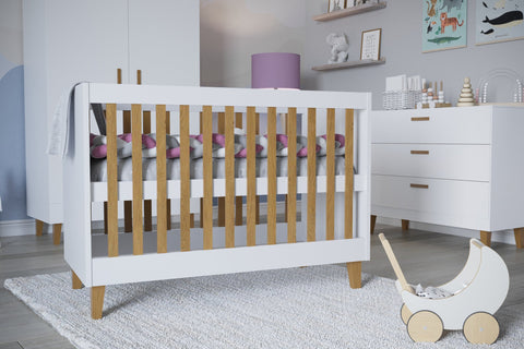 1. White baby cot with oak slats in a modern nursery setting with toys and decor
