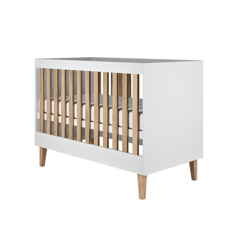 2. White baby cot with oak slats and legs, displayed in a studio environment