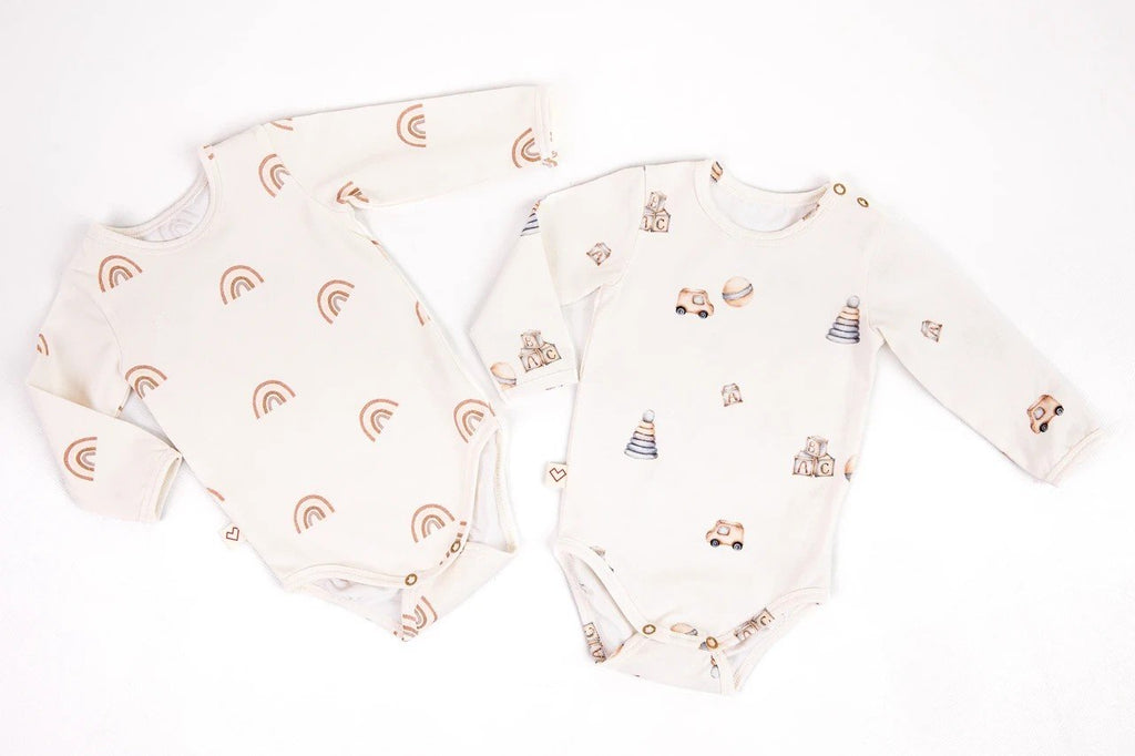 4. Flat lay of two Karloova baby bodysuits, one with rainbow print and the other with toy print, on white background