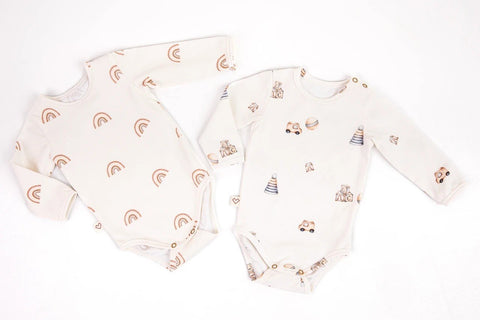 4. Flat lay of two Karloova baby bodysuits, one with rainbow print and the other with toy print, on white background