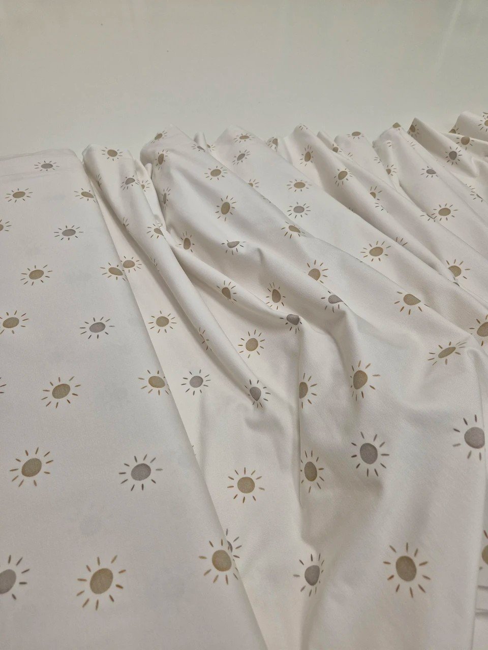 3. Close-up of Karloova baby bodysuit fabric with sun pattern highlighting texture and print