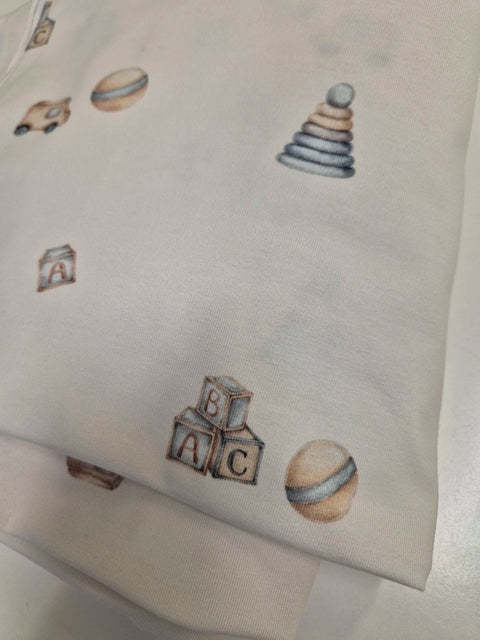3. Close-up of baby bodysuit fabric showing toy print with cars, blocks, and balls, highlighting texture and design