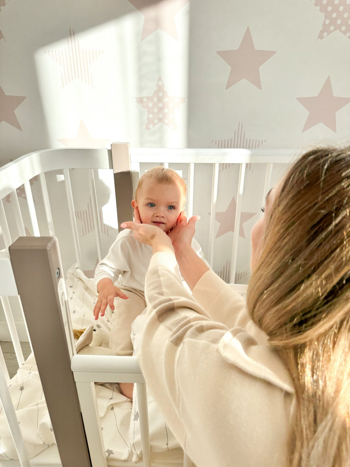 1. Woman playing with baby in KOTTO ELIN crib, cappuccino and white design in star-themed nursery