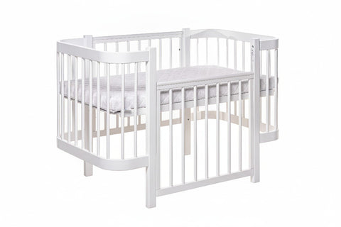 2. White KOTTO ELIN baby crib with mattress in studio setting, showing removable side panel and orthopedic slatted base