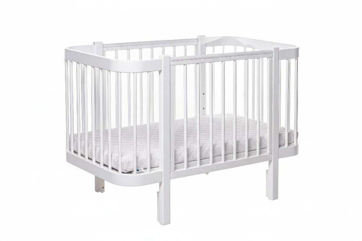 2. White ELIN baby crib with adjustable mattress base heights in studio setting