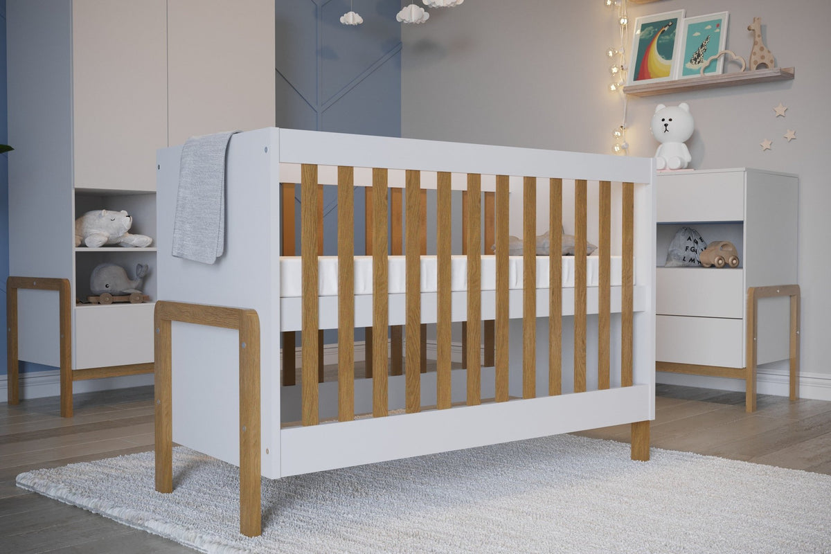1. Scandinavian-style baby crib with white and oak finish in a modern nursery setting