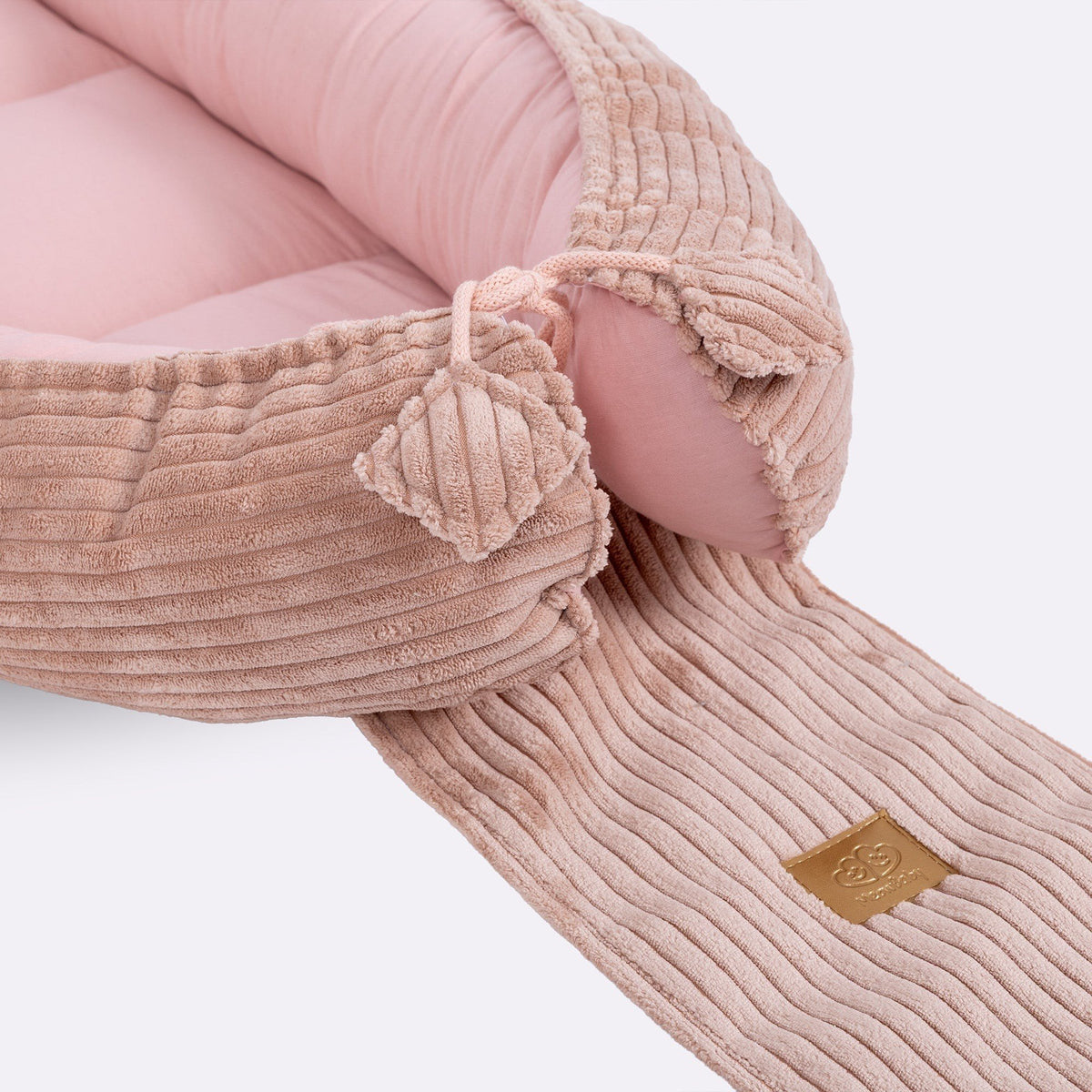 7. Close-up of adjustable ties and ribbed fabric on powder pink baby nest, featuring MeowBaby logo