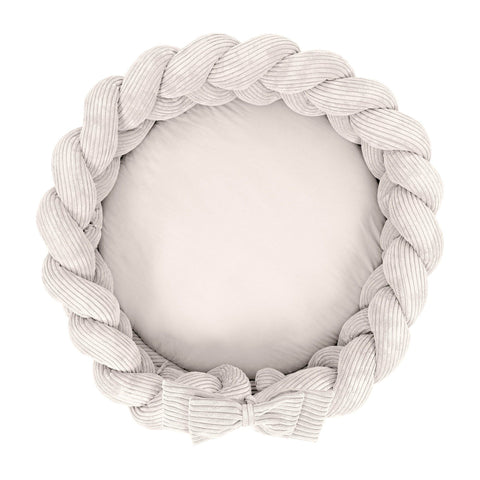 1. Vanilla-colored baby nest with braided crib bumper in ribbed corduroy, shown from above
