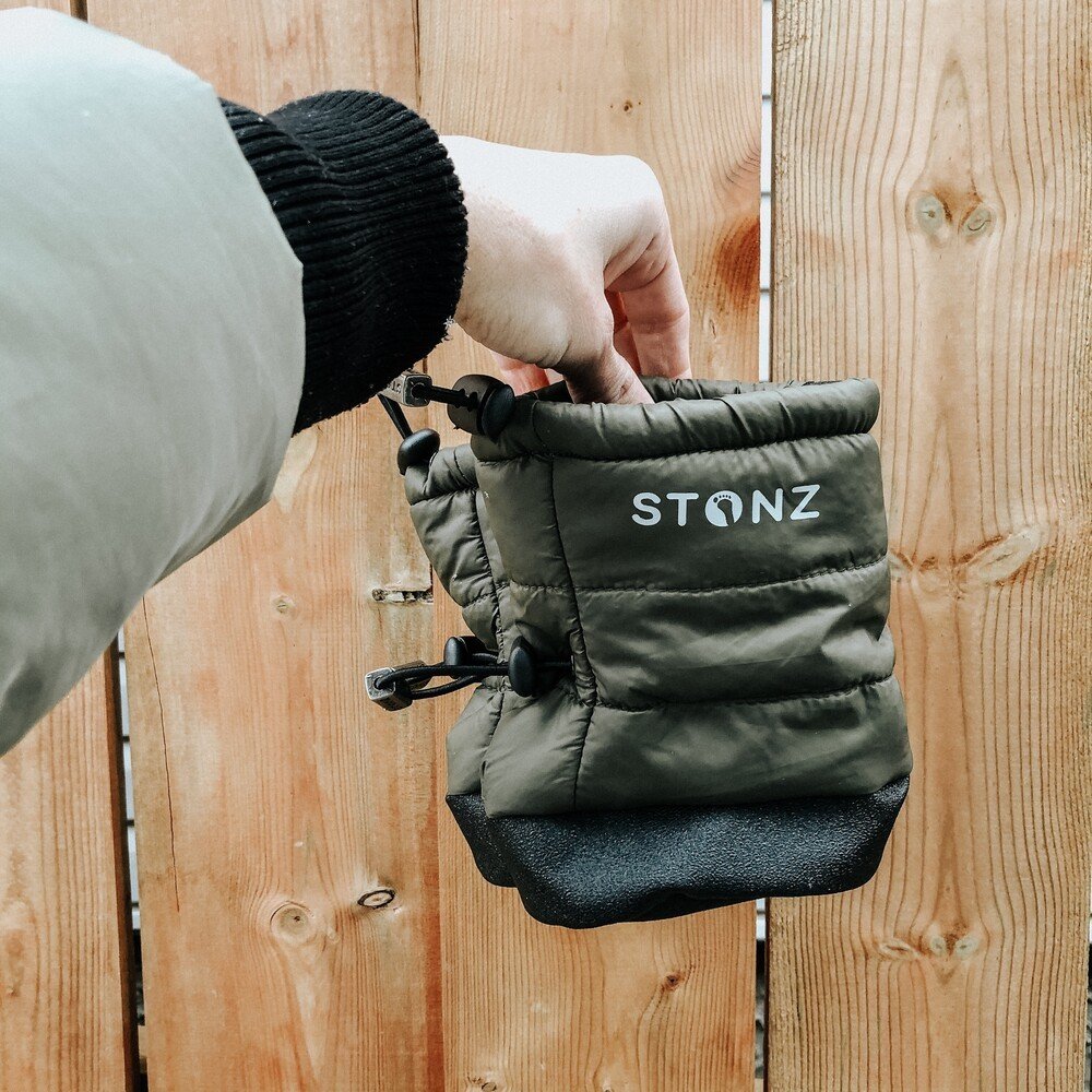 3. Hand holding green Stonz Puffer Bootie with black sole against wooden fence