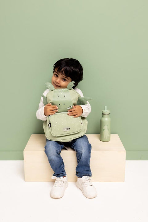 1. Child sitting with green dragon backpack and matching water bottle, green background