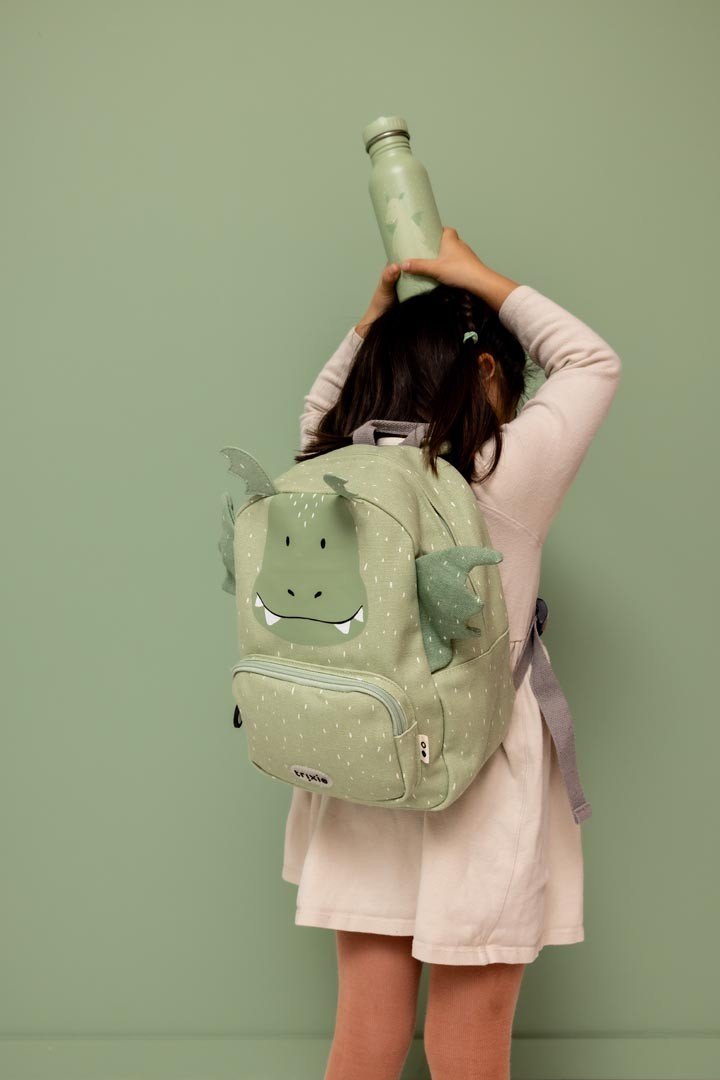 1. Child wearing green dragon backpack holding matching water bottle overhead, green background