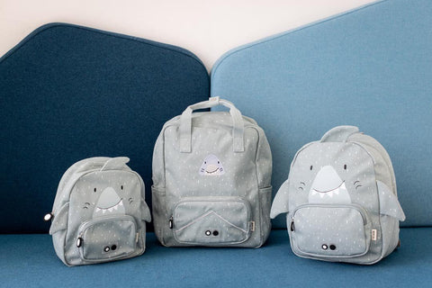 1. Three grey shark-themed backpacks of different sizes on a blue couch