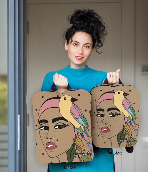4. Woman holding Garbanota BACKPACK JURATE in L and M sizes, featuring unique artwork and smooth fabric