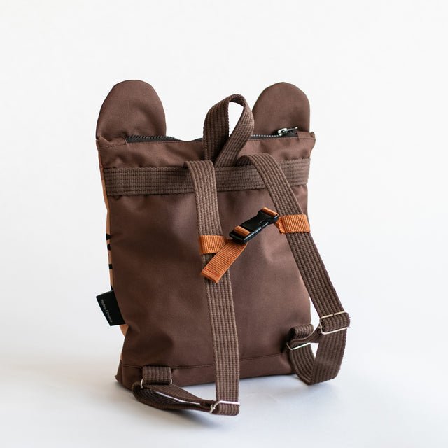 7. Back view of Muni leopard backpack, showing adjustable straps and zipper in studio