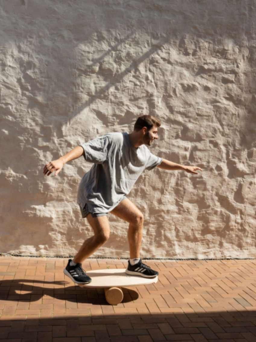 1. Man performing balance exercise on board with roller outdoors