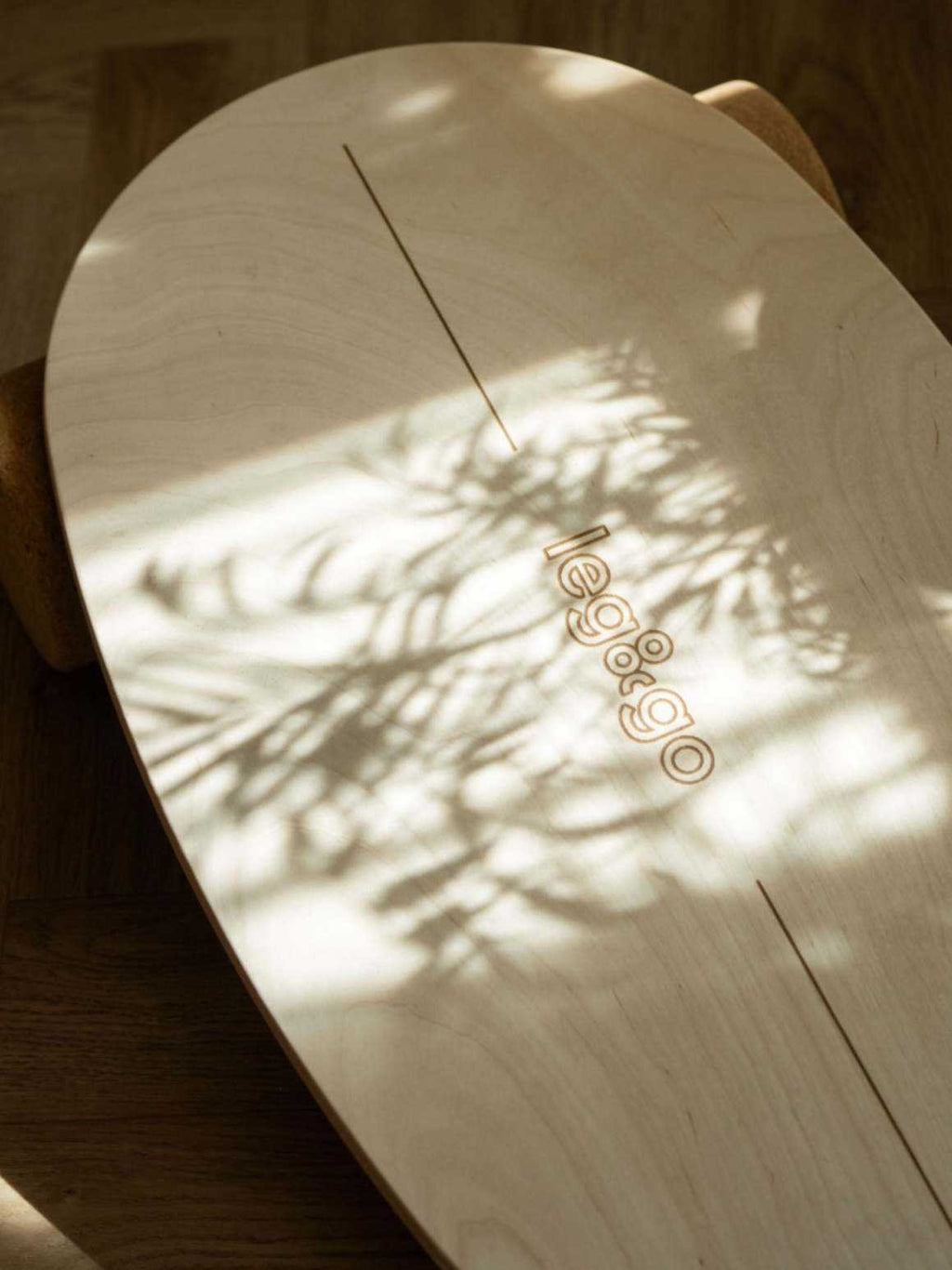3. Close-up of leg&go logo on wooden balance board with artistic shadow play