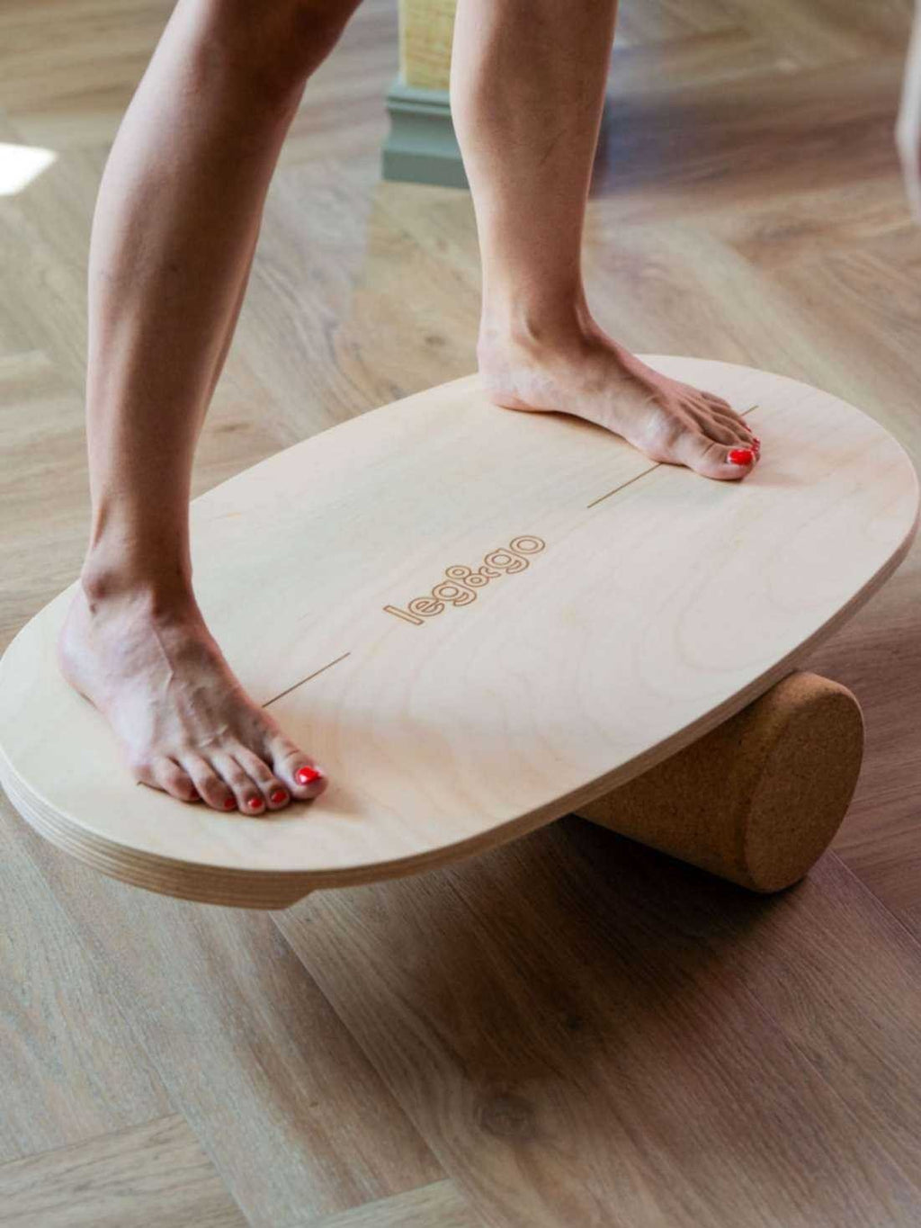 3. Close-up of woman's feet on wooden balance board with cork roller