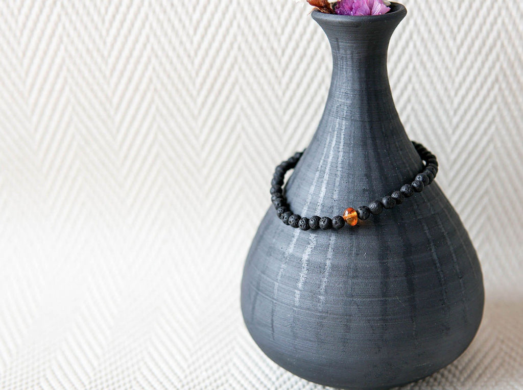 3. Men's Baltic Amber and Black Lava Bracelet by Canary Lava displayed on a dark vase, emphasizing handcrafted design