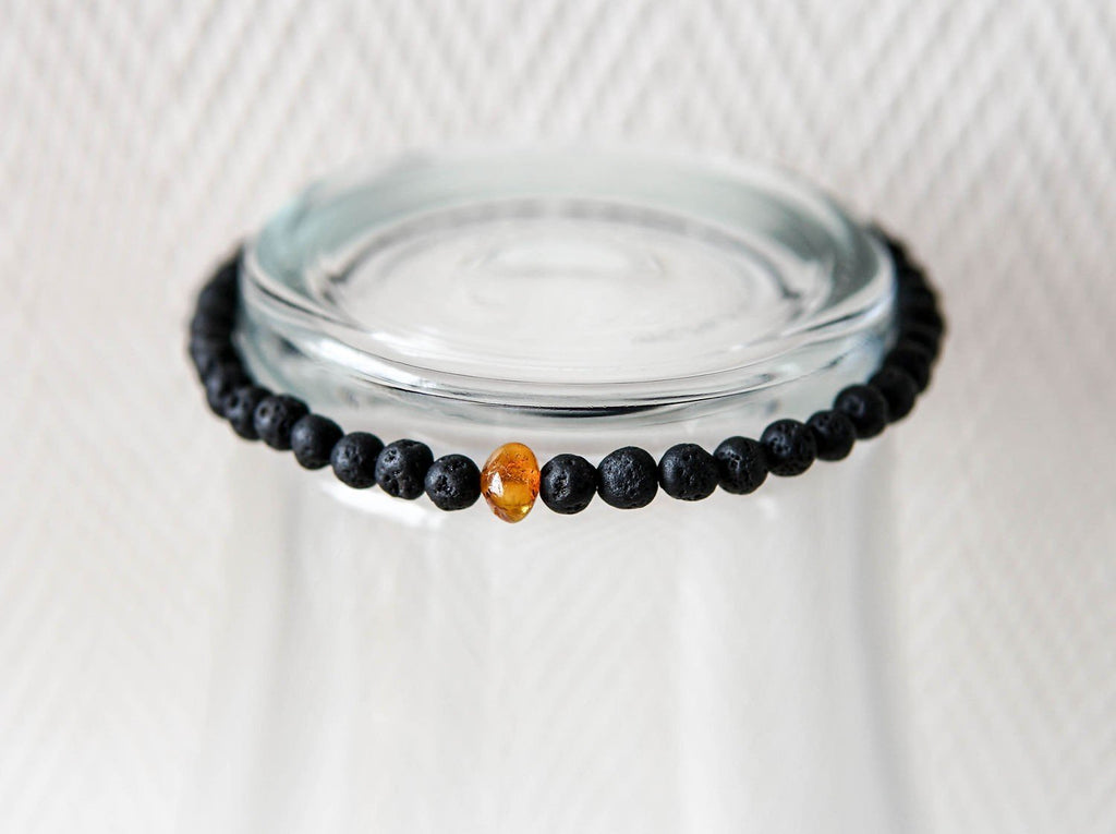 2. Studio shot of men's Baltic Amber and Black Lava Bracelet by Canary Lava, highlighting polished lava stones and amber bead