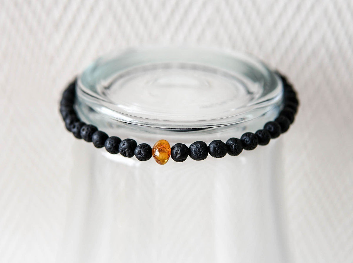 2. Studio shot of men's Baltic Amber and Black Lava Bracelet by Canary Lava, highlighting polished lava stones and amber bead