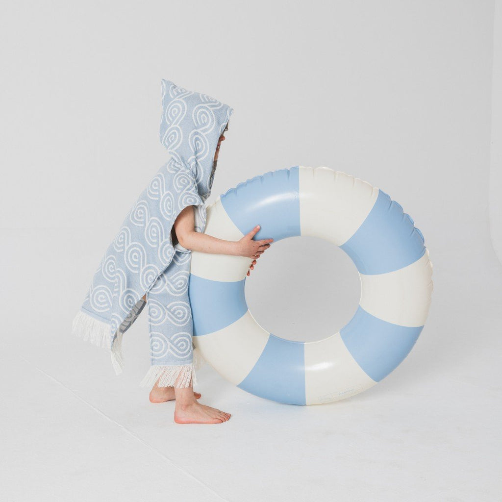 5. Child in light blue Patulove bamboo bath poncho with hood, holding large blue and white inflatable ring