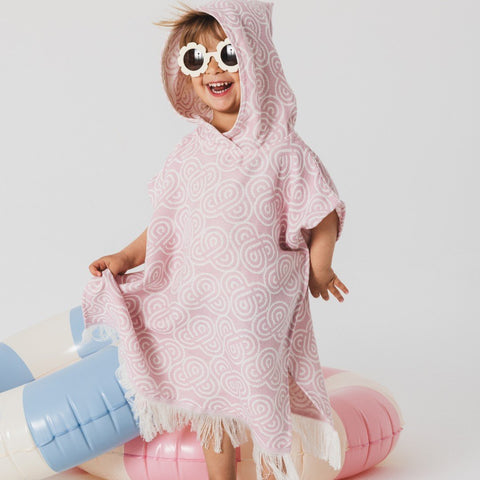 1. Child wearing Patulove rose bamboo bath poncho with hood and sunglasses, standing on inflatable pool toys