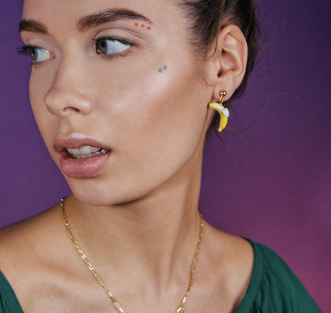 1. Woman wearing SCULP Banana Love earrings with playful design, shown in lifestyle setting
