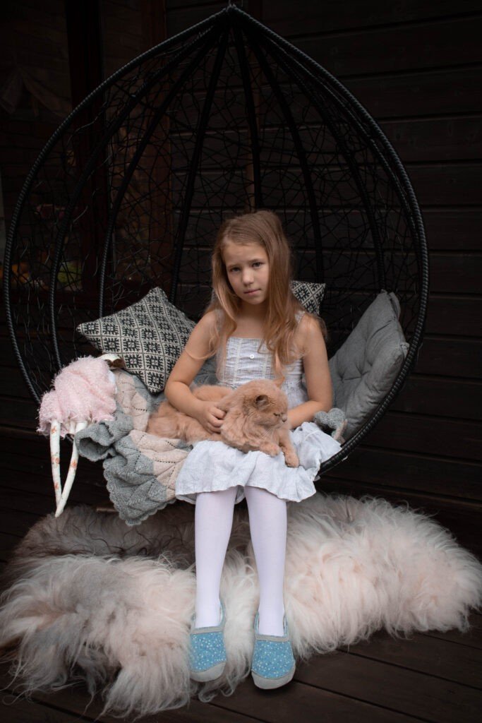 1. Girl wearing blue dotted slippers sitting in a hanging chair with a cat