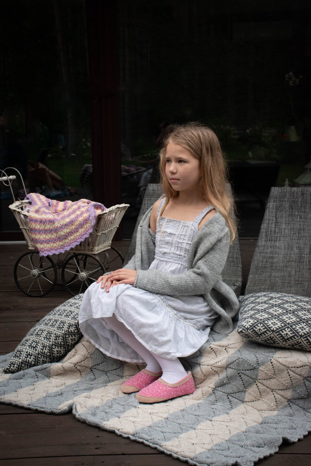 1. Girl wearing pink dotted slippers sitting on a patterned rug outdoors