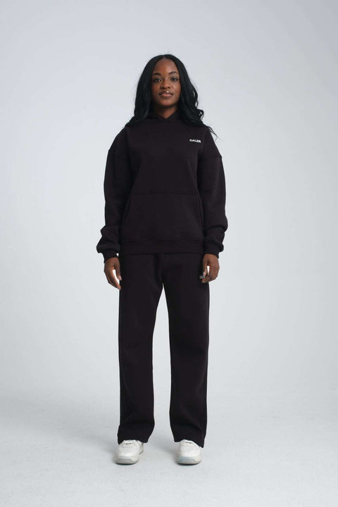 3. Full body view of woman in black oversized hoodie and matching pants, white sneakers, studio setting