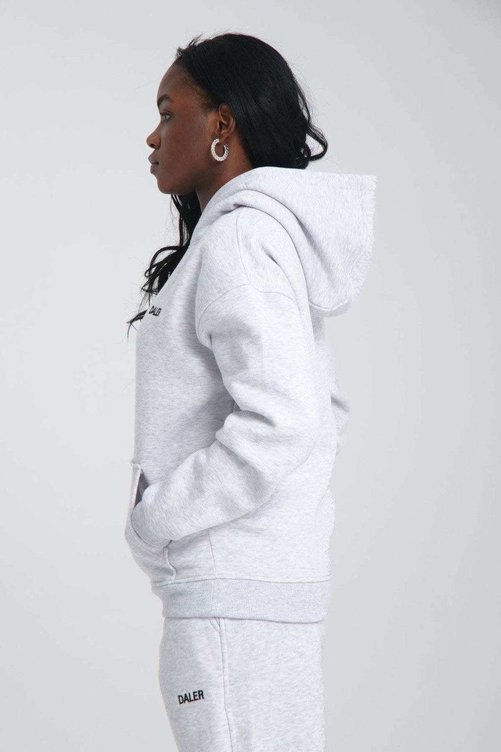 4. Side profile of woman in grey melange hoodie with hood up, studio background