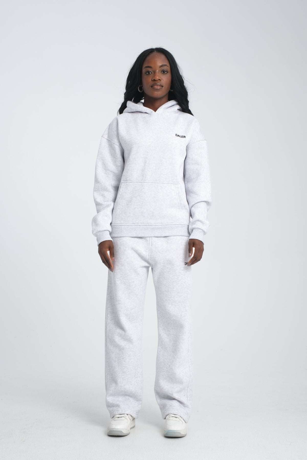 2. Full view of woman in grey melange hoodie and matching pants, standing in studio