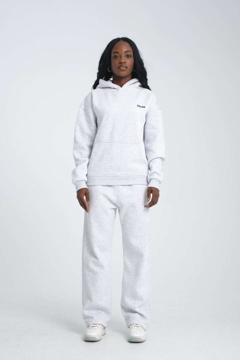 2. Full view of woman in grey melange hoodie and matching pants, standing in studio