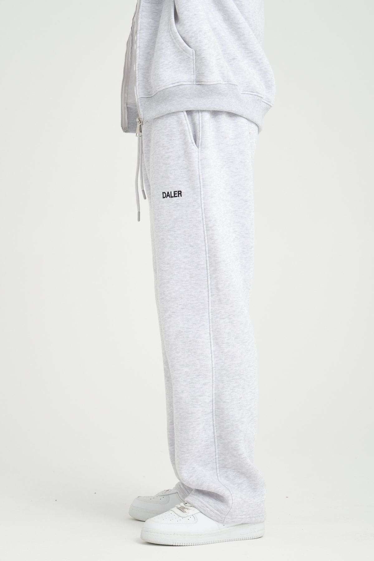 2. Side view of grey melange jogger pants with DALER logo, paired with white sneakers