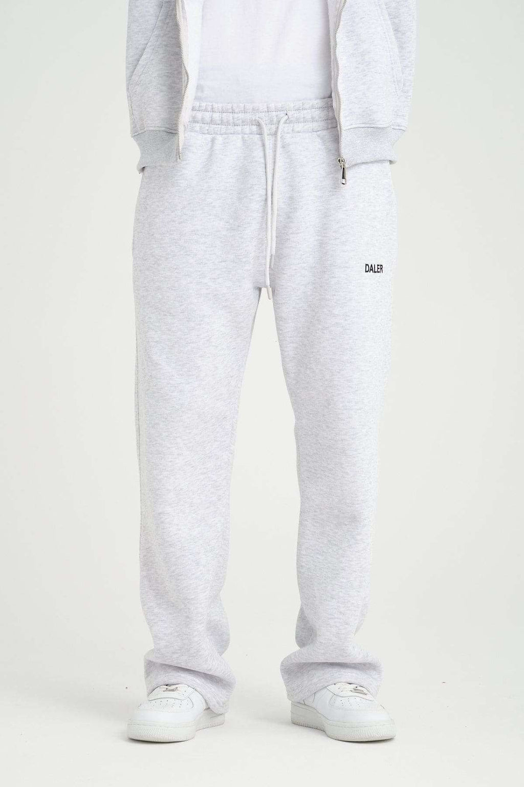 2. Front view of grey melange jogger pants with DALER logo and drawstring waist, paired with white sneakers