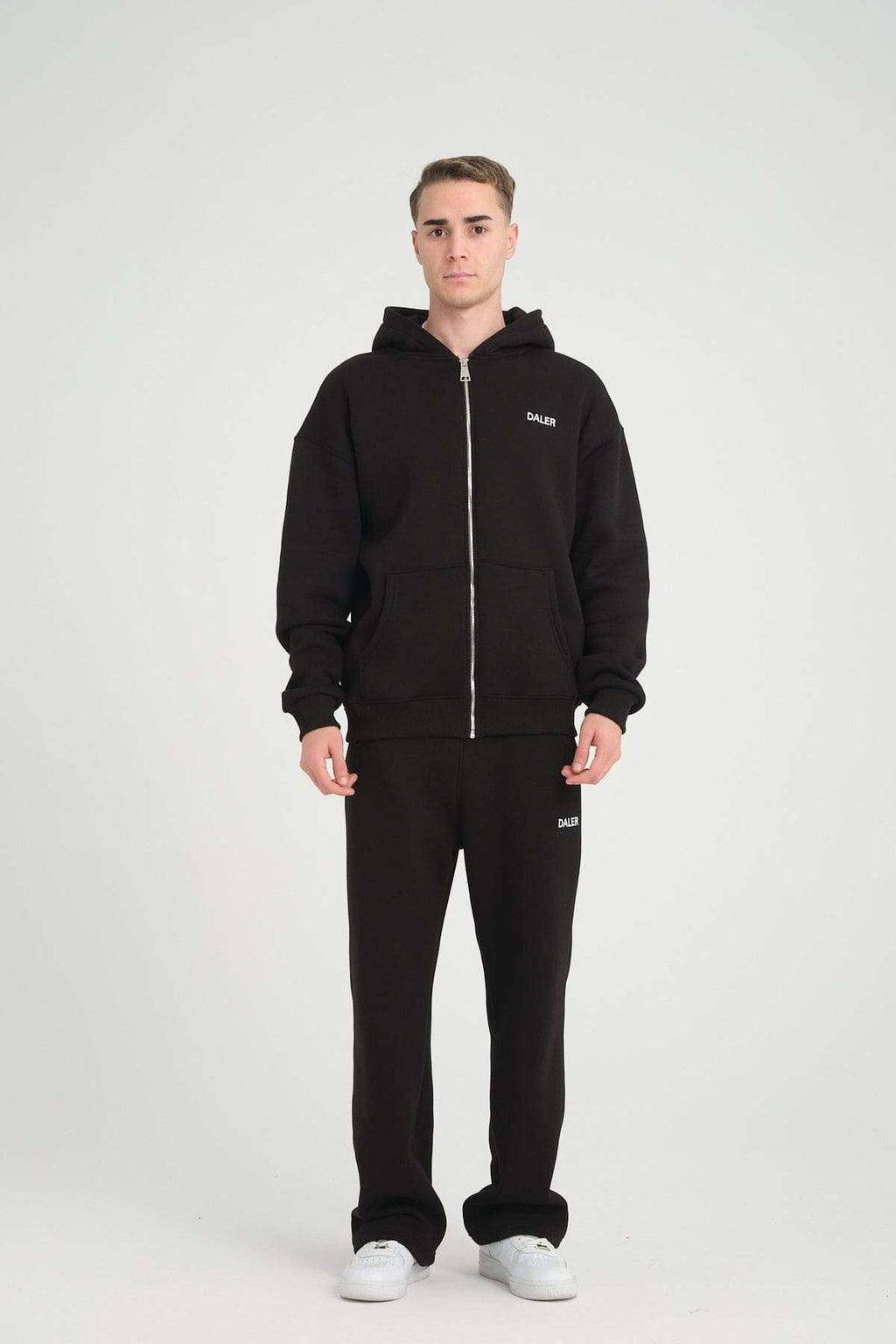2. Full-body view of man in black DalerClo heavyweight zipper hoodie and matching pants, studio setting