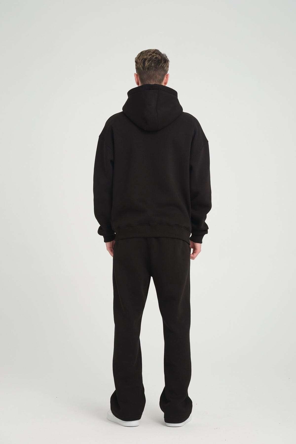 2. Back view of man in black DalerClo heavyweight zipper hoodie, hood up, studio setting