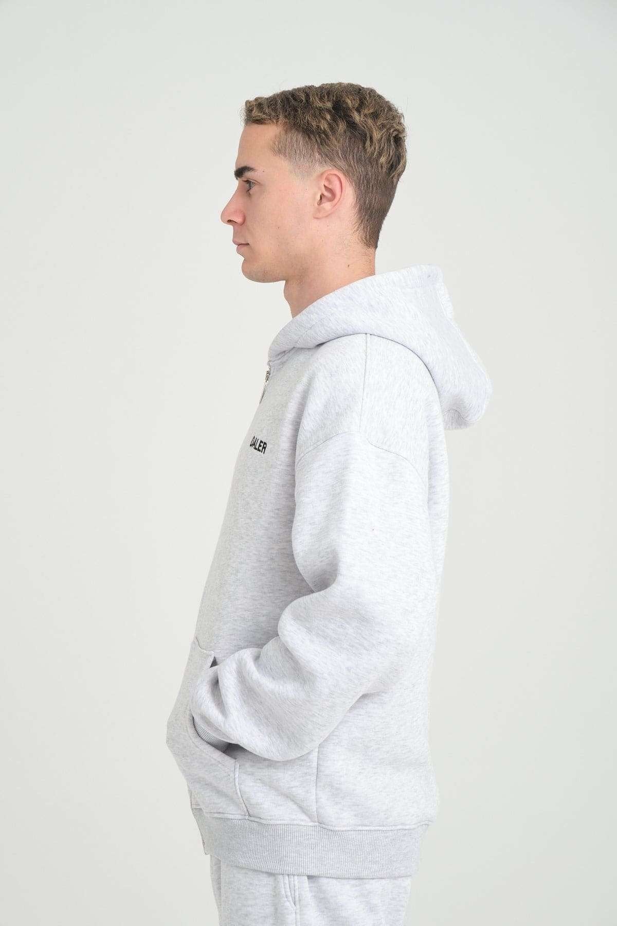 2. Side profile of man wearing grey melange DalerClo hoodie, hands in pockets, studio background