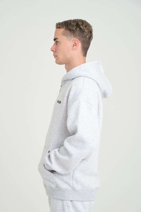 2. Side profile of man wearing grey melange DalerClo hoodie, hands in pockets, studio background