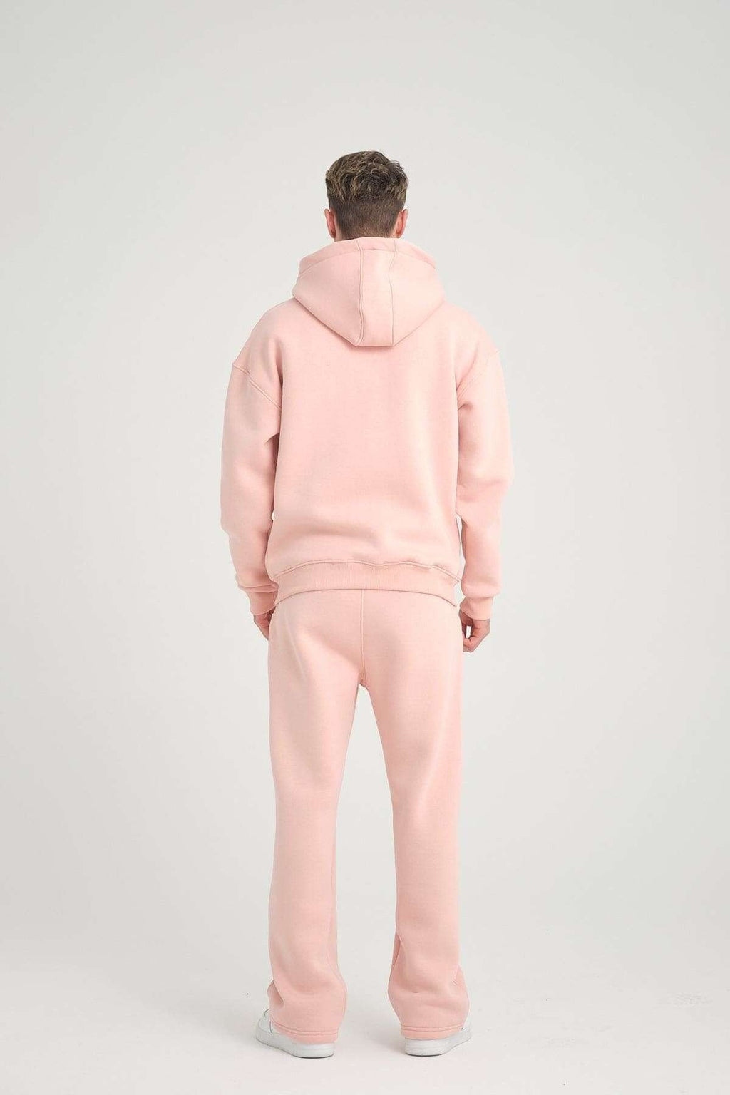1. Back view of man wearing pink oversized zipper hoodie and pants, studio setting