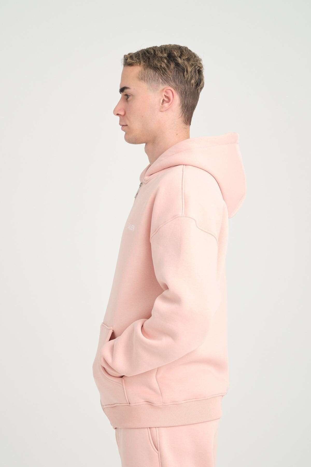 1. Side view of man in pink oversized zipper hoodie with hood up, studio background