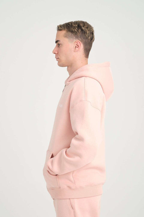1. Side view of man in pink oversized zipper hoodie with hood up, studio background