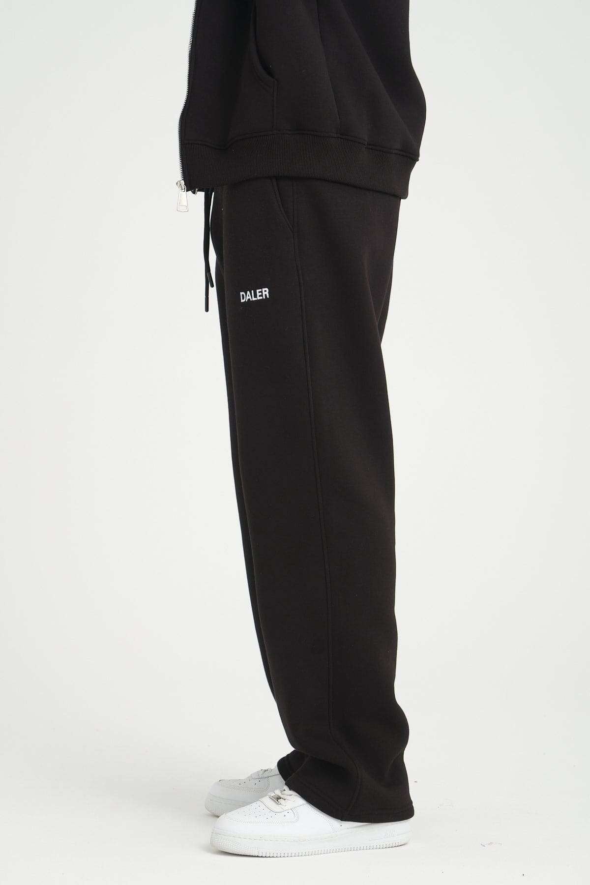 3. Side view of black jogger pants with DALER embroidery, paired with white sneakers