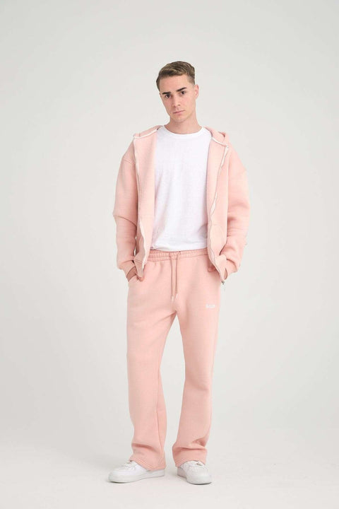 1. Man wearing pink jogger pants and matching hoodie standing in studio setting